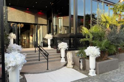 Salle de réception élégante avec tables rondes dressées, chaises transparentes et lustres suspendus.