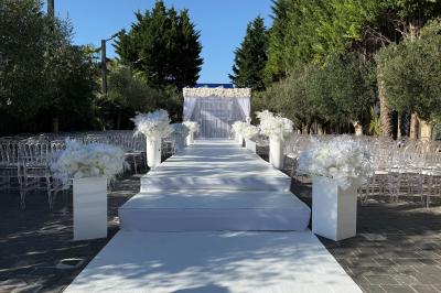 Salle de réception élégante avec tables rondes dressées, chaises transparentes et lustres suspendus.