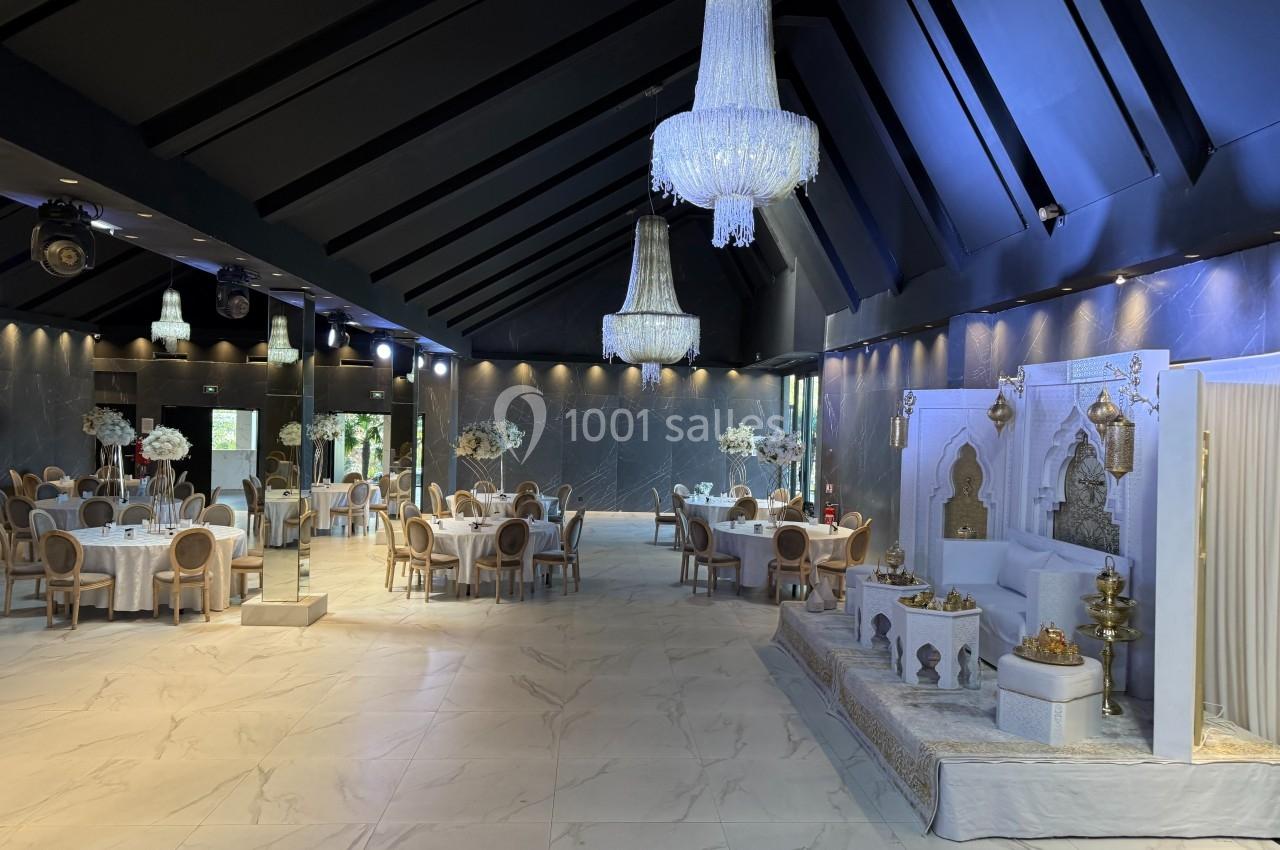 Salle de réception élégante avec tables décorées, lustres imposants et espace aménagé pour une cérémonie.