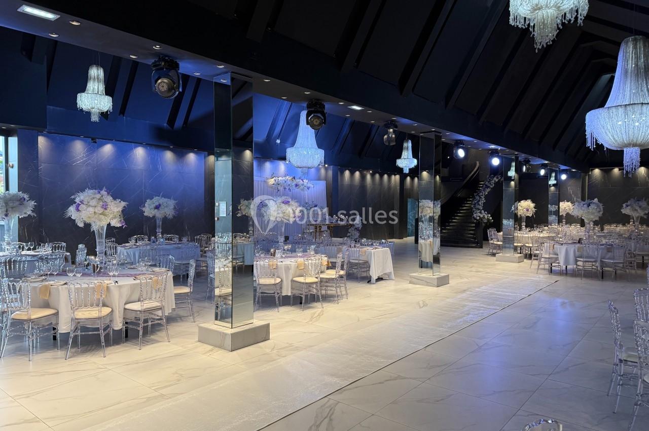 Salle de réception élégante avec tables décorées de fleurs blanches et lustres suspendus.