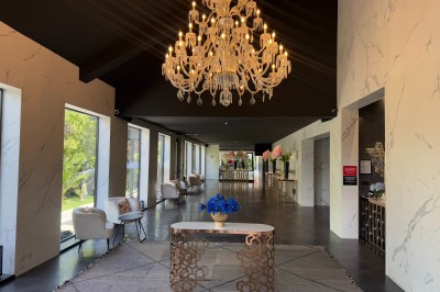 Salle de réception élégante avec tables rondes dressées, chaises transparentes et lustres suspendus.