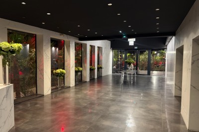 Salle de réception élégante avec tables rondes dressées, chaises transparentes et lustres suspendus.
