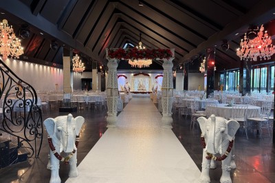 Salle de réception élégante avec tables rondes dressées, chaises transparentes et lustres suspendus.
