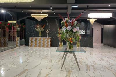 Salle de réception élégante avec tables rondes dressées, chaises transparentes et lustres suspendus.