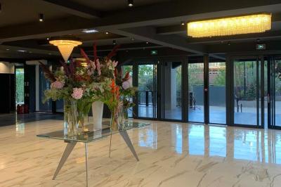 Salle de réception élégante avec tables rondes noires, chaises transparentes, lustres en cristal et décorations végétales.
