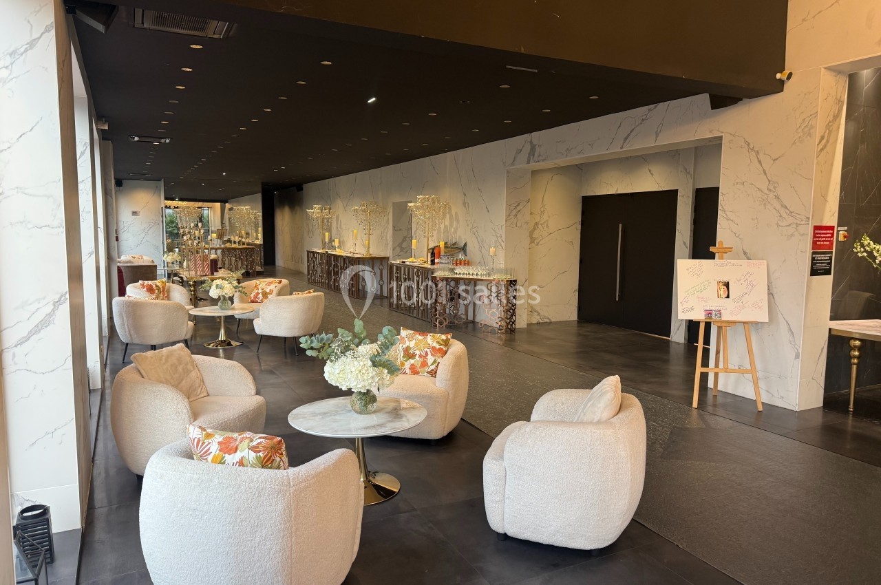 Location salle Bobigny (Seine-Saint-Denis) - Ritz Plazza #1 Espace intérieur moderne avec fauteuils arrondis, tables basses décorées de fleurs et comptoir en arrière-plan.