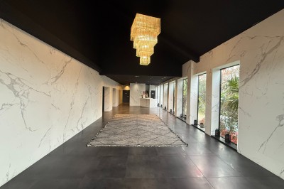 Salle de réception élégante avec tables dressées, chaises transparentes et lustres suspendus dans une ambiance tamisée.