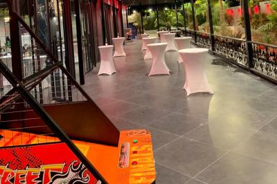 Salle de réception élégante avec tables rondes noires, chaises transparentes, lustres en cristal et décorations végétales.
