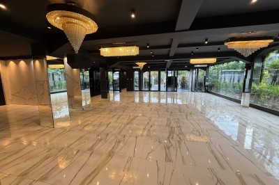Salle de réception élégante avec tables dressées, chaises transparentes et lustres suspendus dans une ambiance tamisée.