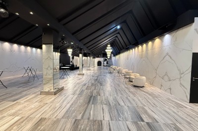 Salle de réception élégante avec tables dressées, chaises transparentes et lustres suspendus dans une ambiance tamisée.