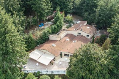 Vue aérienne d'une vallée verdoyante avec des collines, des villages et un ciel partiellement nuageux à l'horizon.