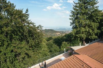 Vue aérienne d'une vallée verdoyante avec des collines, des villages et un ciel partiellement nuageux à l'horizon.