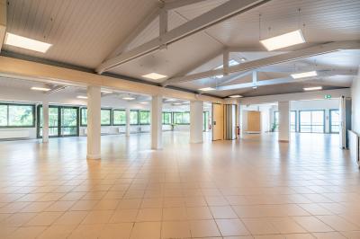 Vue aérienne d'une vallée verdoyante avec des collines, des villages et un ciel partiellement nuageux à l'horizon.