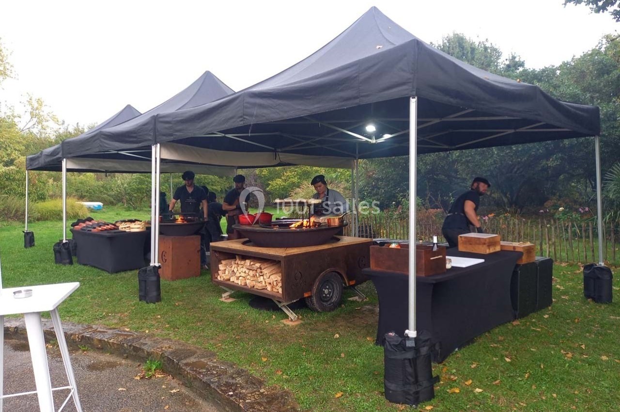 Quatre stands sous des tentes noires proposant de la nourriture en extérieur, avec des cuisiniers en activité.