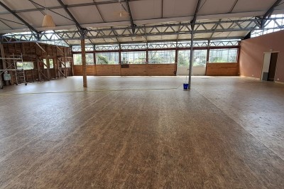 Miniature Location salle Névez (Finistère) - Jardins et Serres de Rospico #13 Grande salle lumineuse avec sol rouge, toit en verre, chaises blanches, comptoir et décorations suspendues.