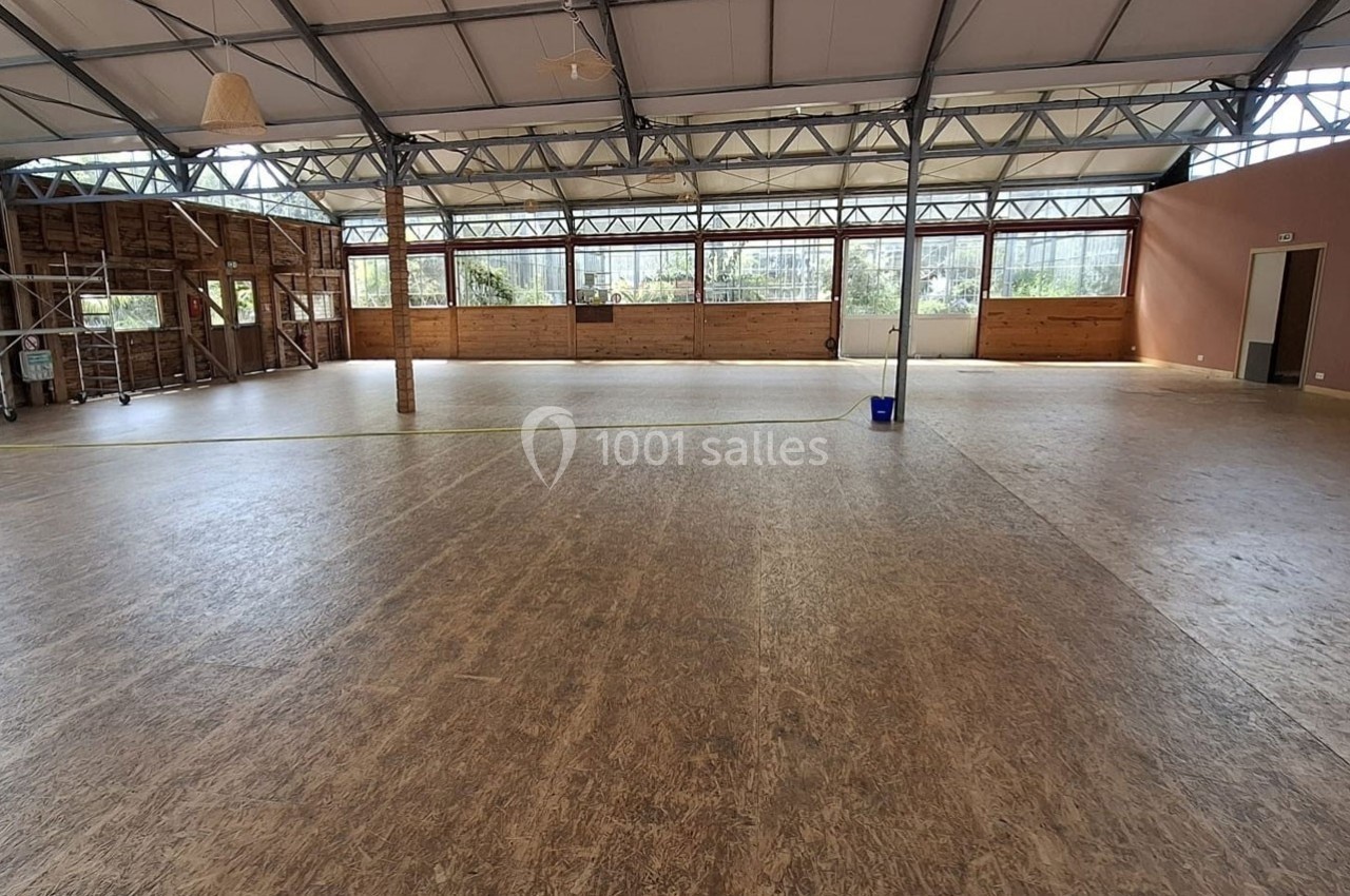 Salle spacieuse avec un sol en parquet, des murs en bois et de grandes baies vitrées laissant entrer la lumière naturelle.