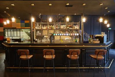 Salle de restaurant moderne avec murs en briques, tables en bois, chaises en cuir et éclairage tamisé.