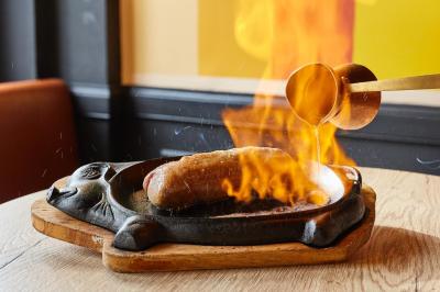 Salle de restaurant moderne avec murs en briques, tables en bois, chaises en cuir et éclairage tamisé.