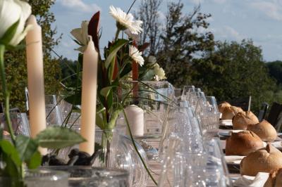 Centre de table floral avec roses blanches et feuillage, entouré de verres en cristal sur une table dressée en extérieur.