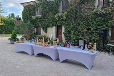 Portail en bois décoré de plantes grimpantes, donnant sur une cour ensoleillée bordée d'arbres et de végétation.