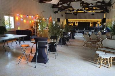 Portail en bois décoré de plantes grimpantes, donnant sur une cour ensoleillée bordée d'arbres et de végétation.