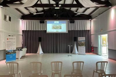 Portail en bois décoré de plantes grimpantes, donnant sur une cour ensoleillée bordée d'arbres et de végétation.