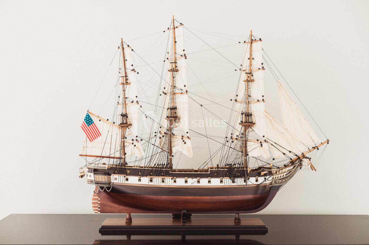 Maquette détaillée d'un voilier ancien avec trois mâts, exposée sur une surface sombre.