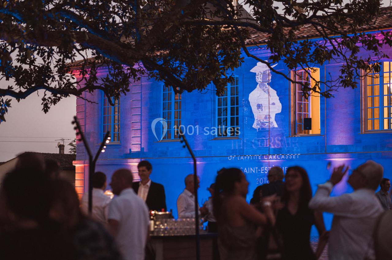 Groupe de personnes discutant en soirée devant un bâtiment illuminé avec une projection artistique sur sa façade.