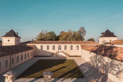 Vue aérienne d'un domaine viticole entouré de vignes, avec un fleuve visible à l'horizon.