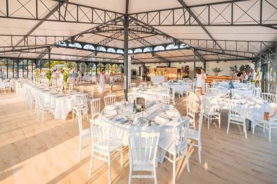 Bâtiment moderne avec une structure en verre et métal entouré de verdure, sous un ciel dégagé.