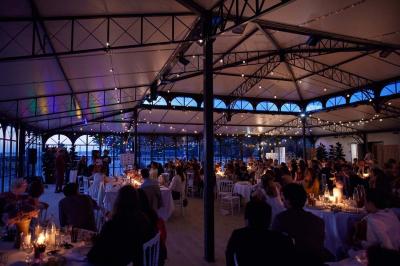 Bâtiment moderne avec une structure en verre et métal entouré de verdure, sous un ciel dégagé.