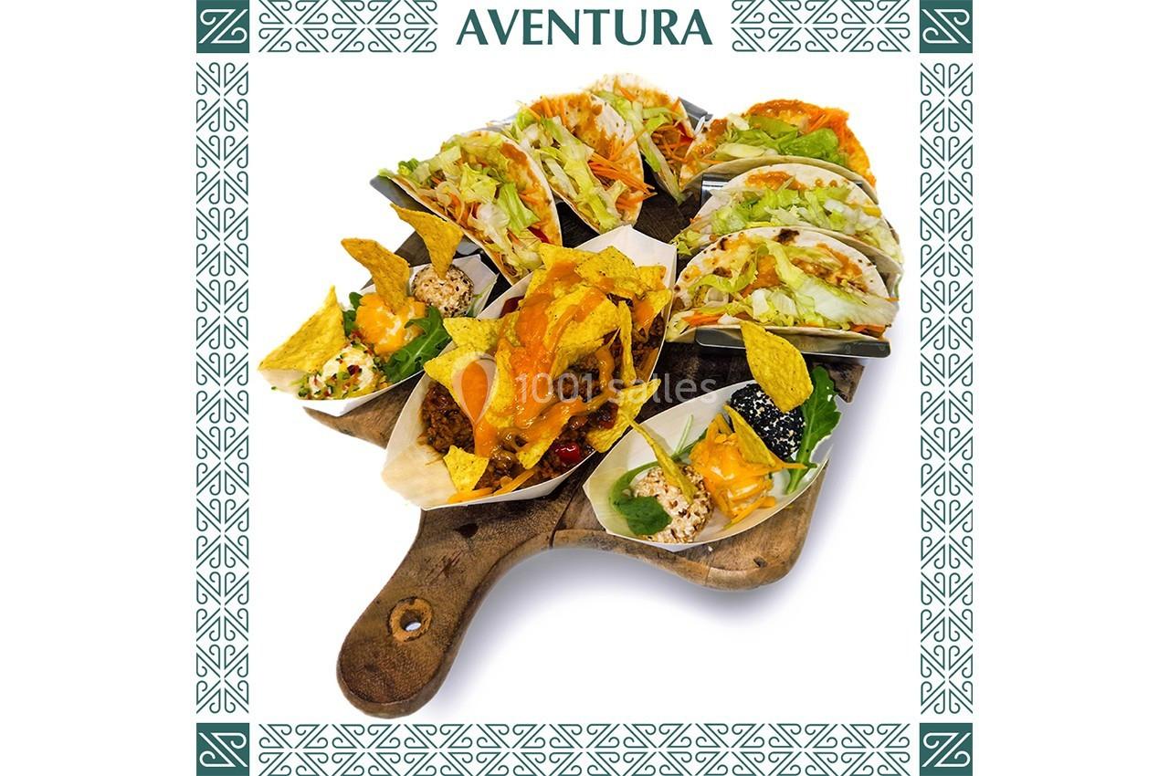 Plateau en bois garni de tacos variés avec légumes, sauces et nachos, présenté sur fond décoratif.