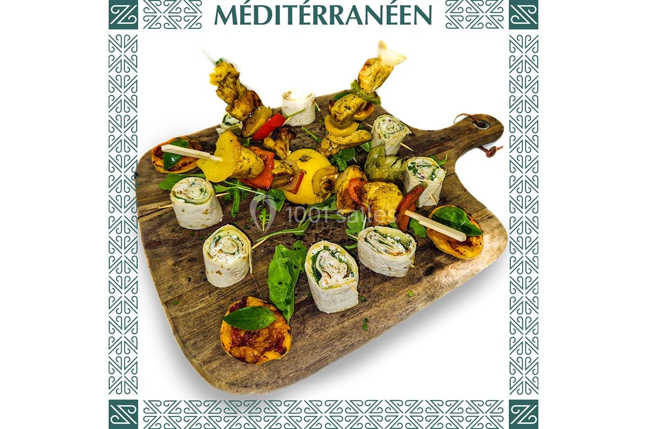 Plateau en bois garni de brochettes, roulés garnis, légumes grillés et herbes fraîches, style méditerranéen.