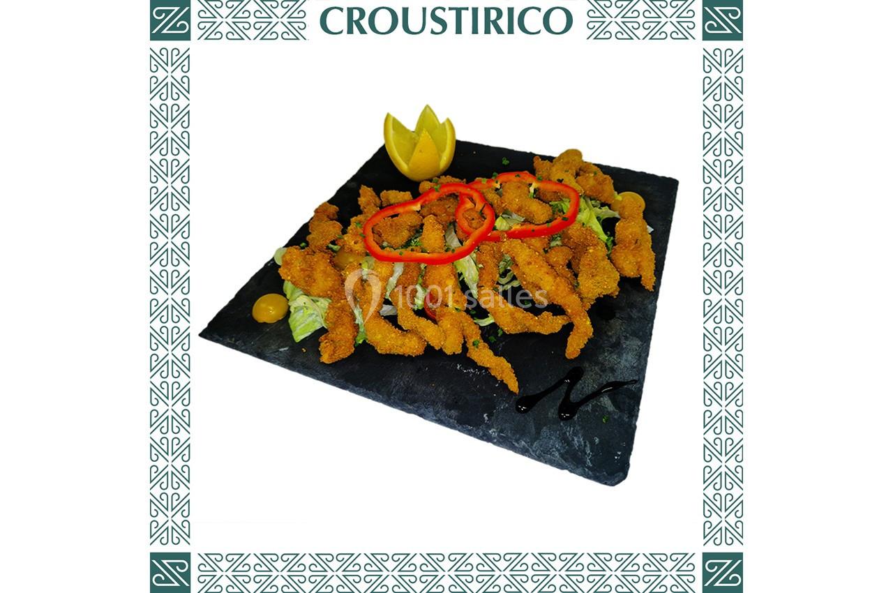 Assiette de beignets de poisson sur lit de salade, décorée de citron sculpté et de rondelles de piment rouge.