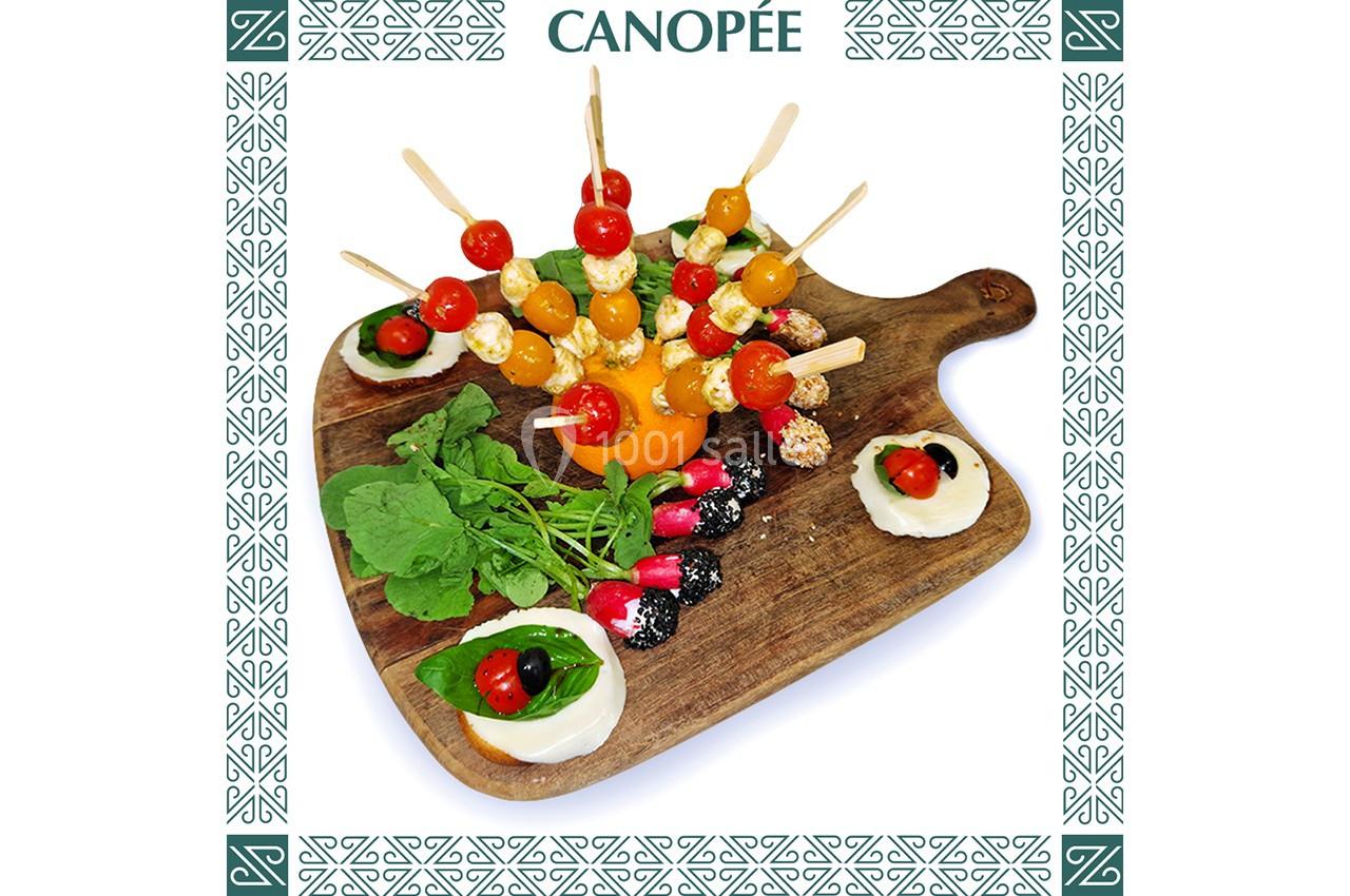 Plateau en bois avec brochettes de tomates cerises, fromage, herbes fraîches et sauces décorées.