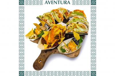 Plateau en bois garni de tacos variés avec garnitures colorées, présenté sur un fond décoratif.