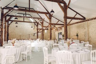 Des tables et chaises jaunes sont disposées sur une terrasse en plein air, près d'un arbre et d'un bâtiment clair.
