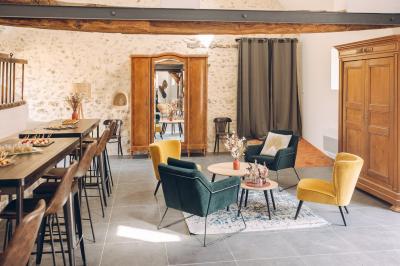 Des tables et chaises jaunes sont disposées sur une terrasse en plein air, près d'un arbre et d'un bâtiment clair.