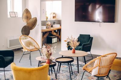Des tables et chaises jaunes sont disposées sur une terrasse en plein air, près d'un arbre et d'un bâtiment clair.
