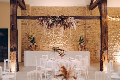 Des tables et chaises jaunes sont disposées sur une terrasse en plein air, près d'un arbre et d'un bâtiment clair.