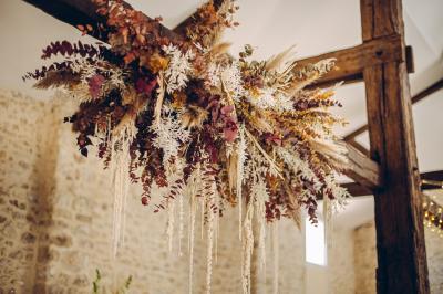 Des tables et chaises jaunes sont disposées sur une terrasse en plein air, près d'un arbre et d'un bâtiment clair.