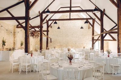 Des tables et chaises jaunes sont disposées sur une terrasse en plein air, près d'un arbre et d'un bâtiment clair.