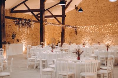 Des tables et chaises jaunes sont disposées sur une terrasse en plein air, près d'un arbre et d'un bâtiment clair.