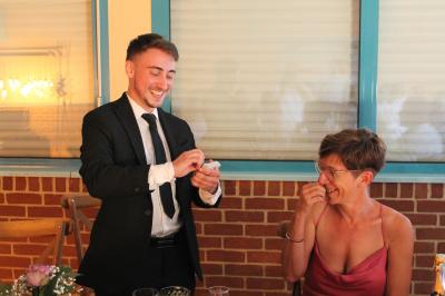 Un magicien sur scène tenant une baguette devant un accessoire éclairé dans un décor sombre.