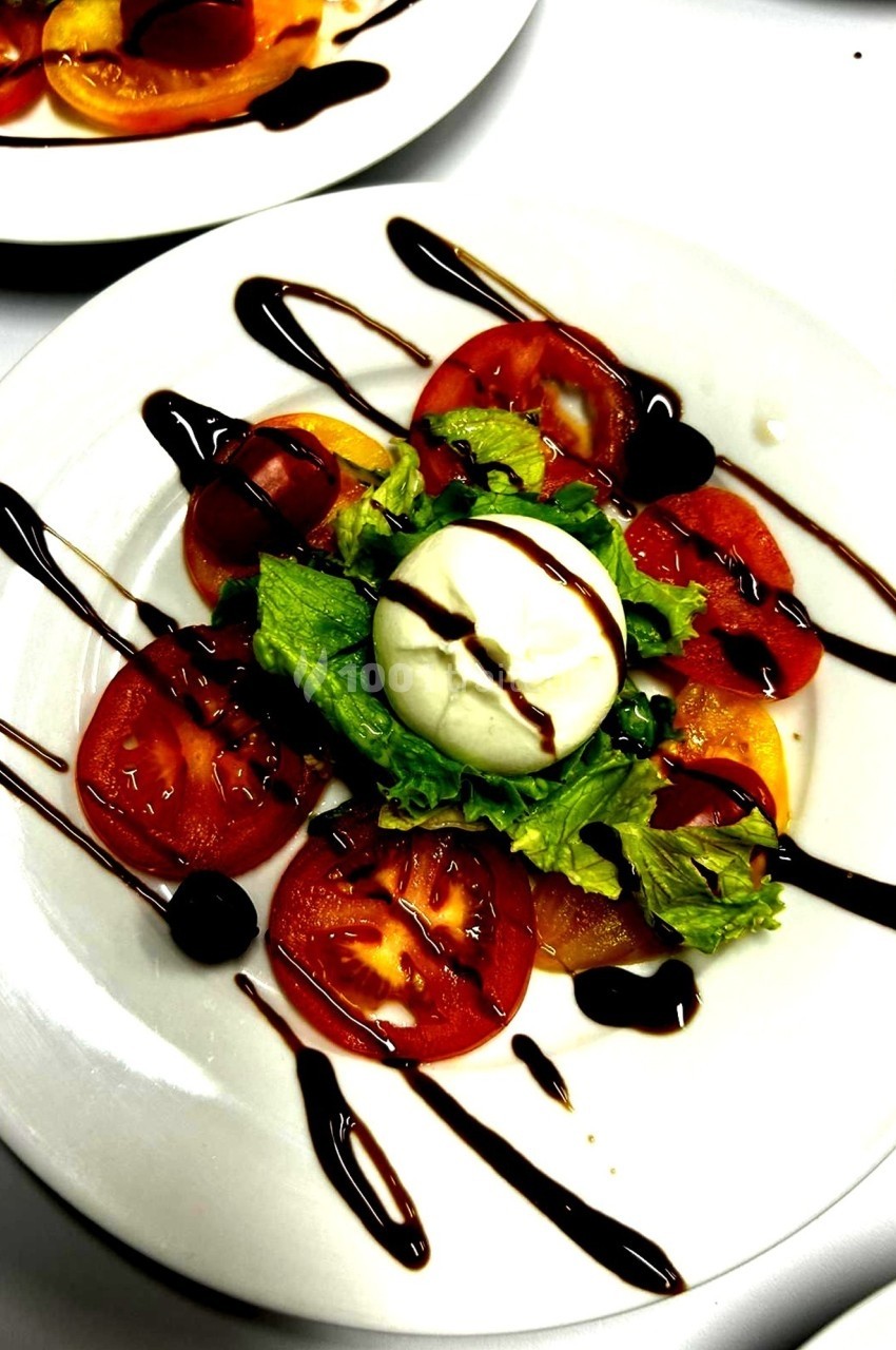 Assiette de salade composée de tomates, mozzarella, laitue et filet de vinaigre balsamique.