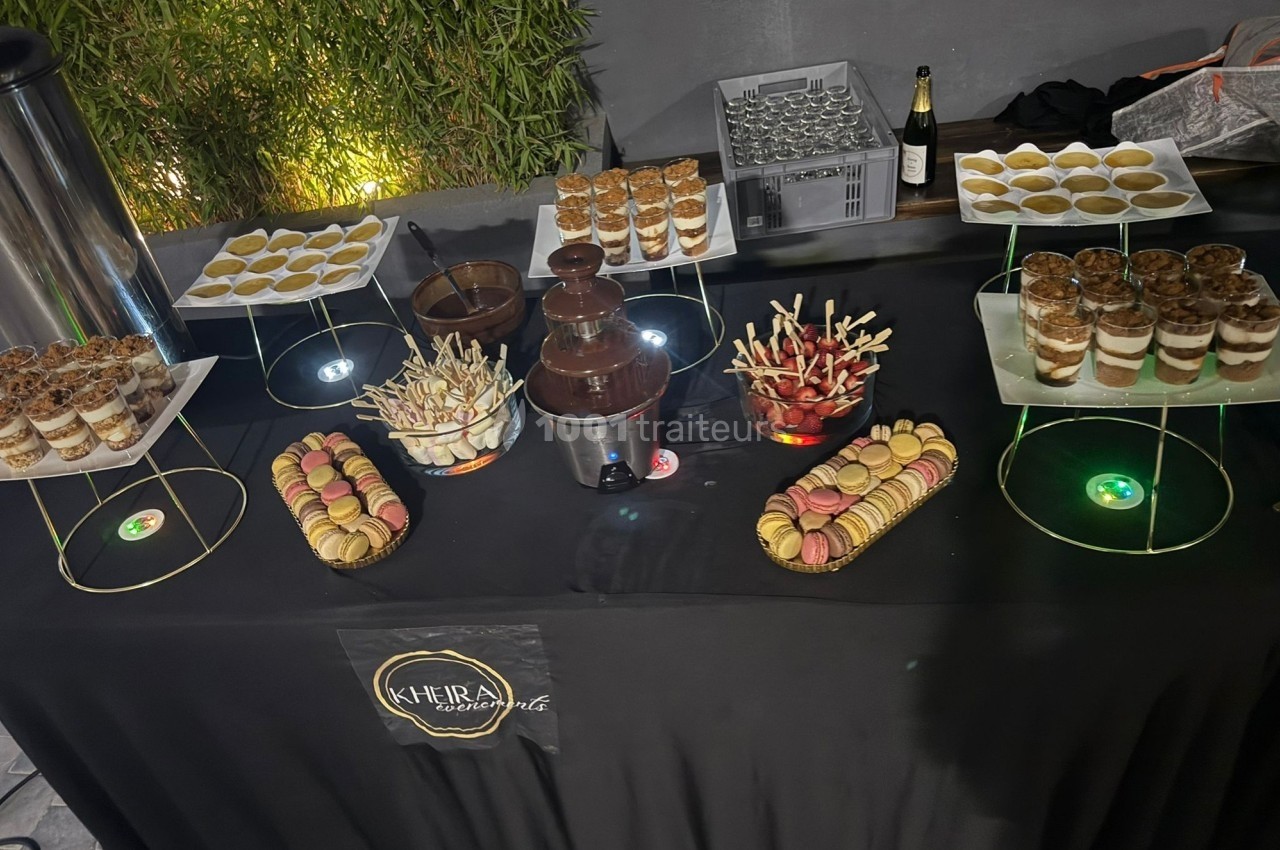 Table de desserts variés avec macarons, verrines, fontaine de chocolat et brochettes de fruits, décorée sobrement.