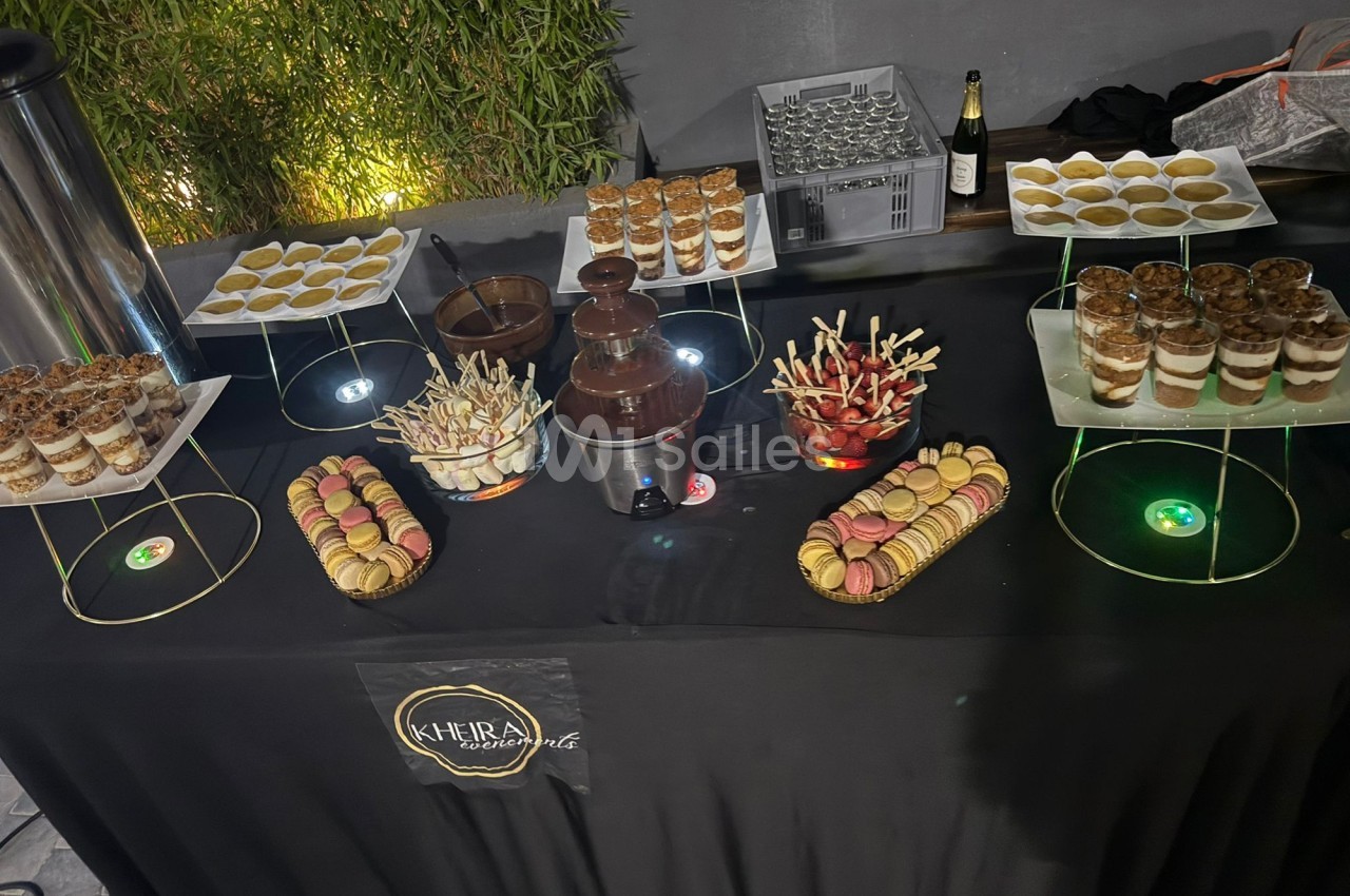 Table de desserts variés avec macarons, verrines, fontaine de chocolat et brochettes de fruits, décorée sobrement.