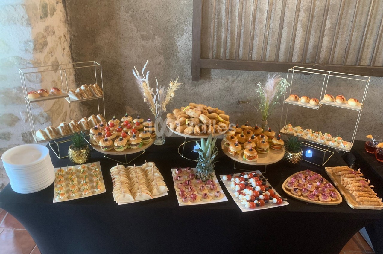 Buffet de pièces cocktail variées comprenant canapés, mini-sandwichs, viennoiseries et amuse-bouches sur une table noire.