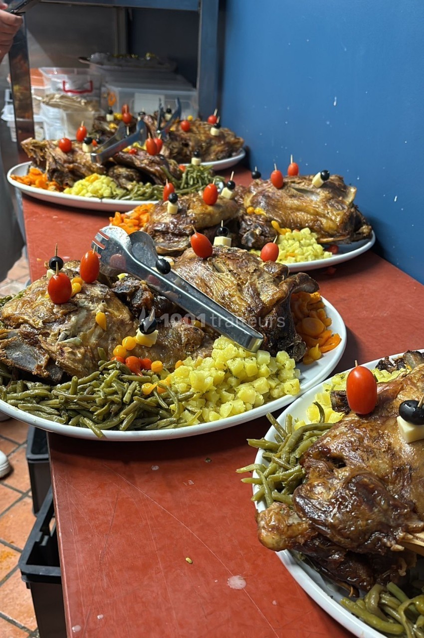 Assiettes garnies de viande rôtie, haricots verts, pommes de terre sautées et légumes décoratifs sur un plan de travail.