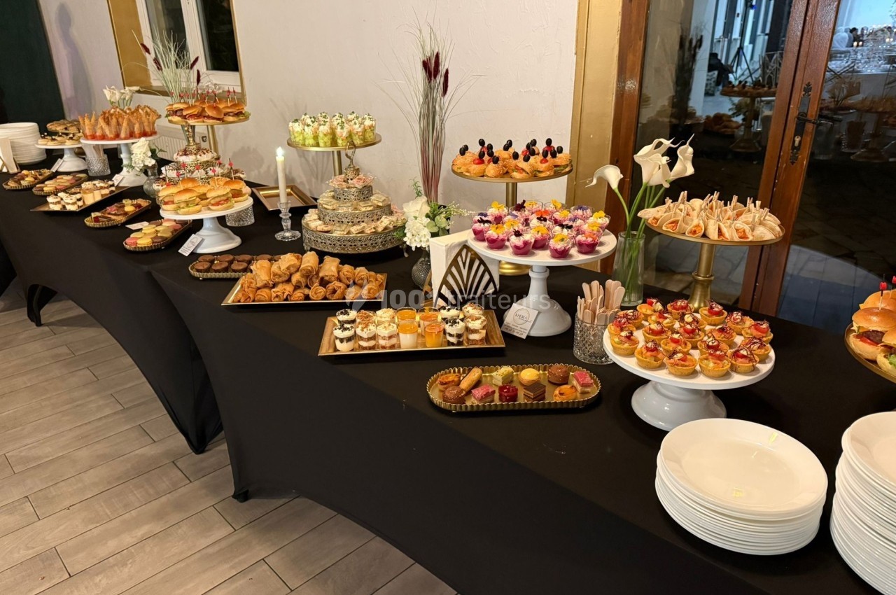 Buffet de desserts et amuse-bouches variés disposés sur des tables noires avec une présentation soignée.